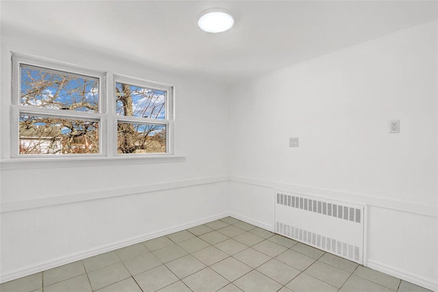 tiled spare room featuring radiator heating unit