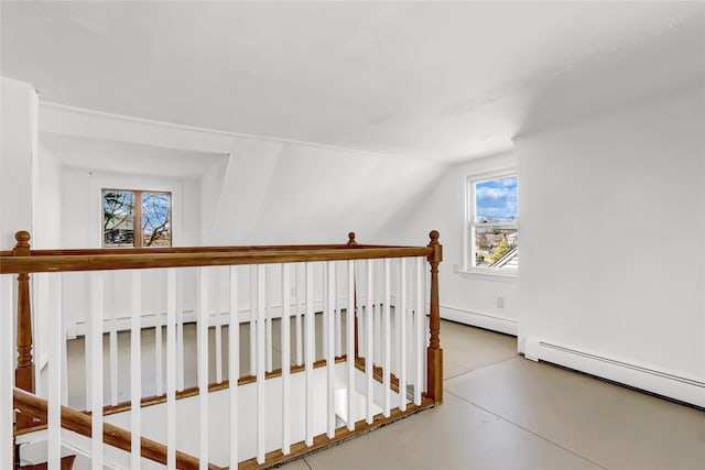 staircase with vaulted ceiling, concrete floors, and baseboard heating