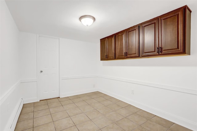 tiled empty room featuring a baseboard heating unit