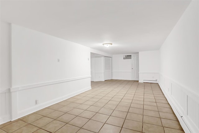 tiled spare room with a baseboard radiator and a wall unit AC