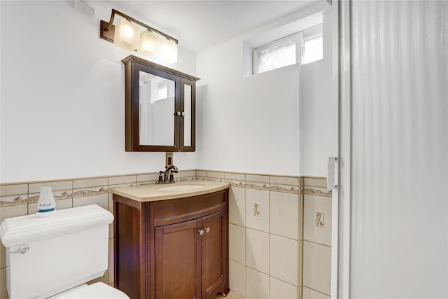 bathroom with vanity, tile walls, and toilet