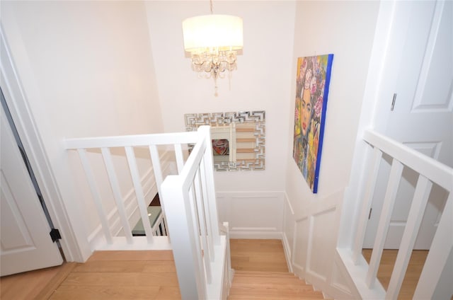 stairs with hardwood / wood-style flooring and an inviting chandelier