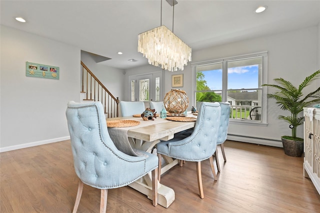 dining room featuring an inviting chandelier, a baseboard heating unit, a wealth of natural light, and light wood-type flooring