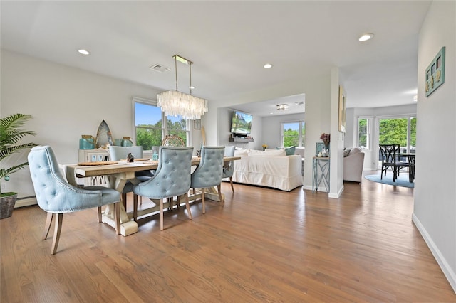 dining space with wood-type flooring, a chandelier, and a baseboard radiator