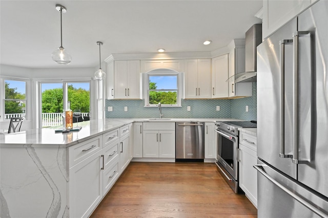 kitchen with premium appliances, wall chimney range hood, sink, and white cabinets