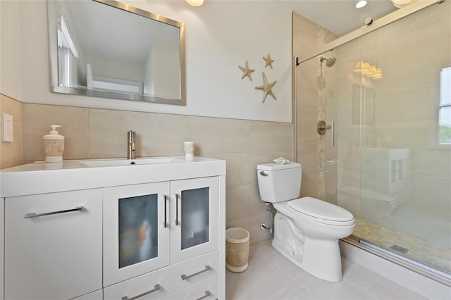 bathroom with vanity, a shower with shower door, tile walls, and toilet