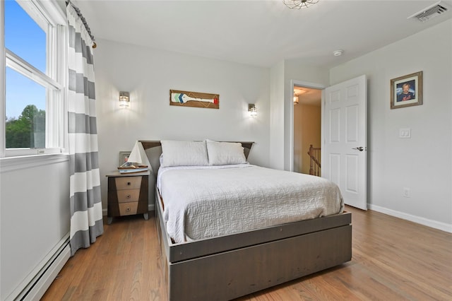 bedroom featuring baseboard heating and light hardwood / wood-style floors