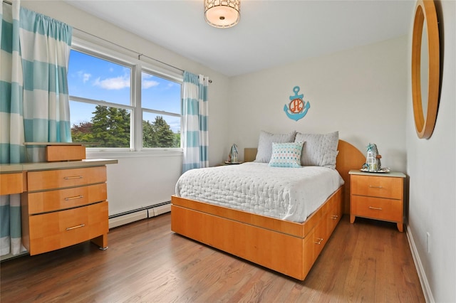 bedroom featuring light wood-type flooring and a baseboard heating unit