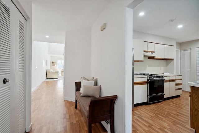 kitchen featuring white cabinets, range with gas stovetop, and light hardwood / wood-style flooring