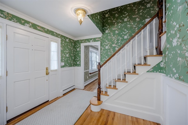 foyer with crown molding, light hardwood / wood-style flooring, and a baseboard heating unit