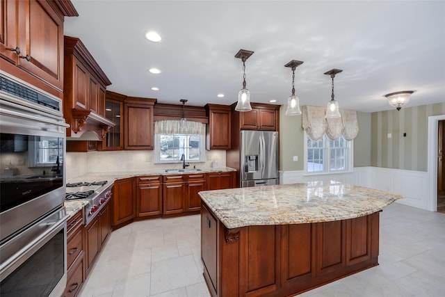 kitchen featuring sink, appliances with stainless steel finishes, hanging light fixtures, backsplash, and a kitchen island