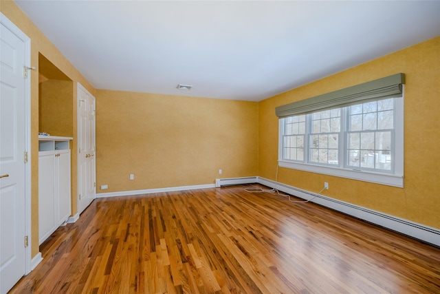 unfurnished room featuring hardwood / wood-style flooring and baseboard heating