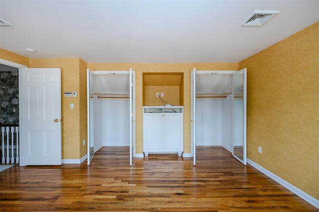 unfurnished bedroom featuring two closets and wood-type flooring