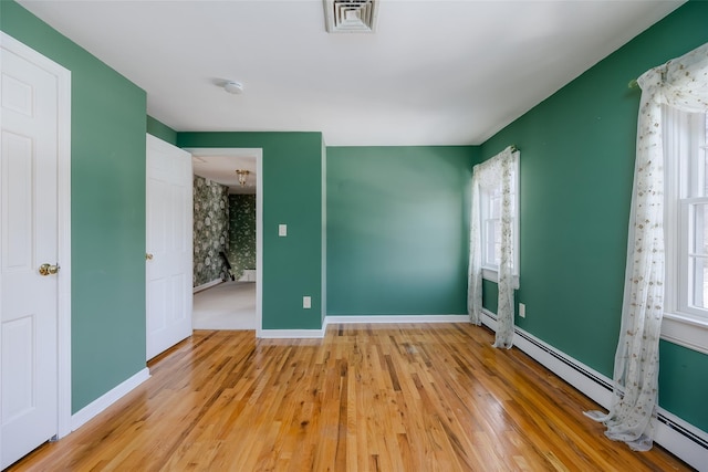 unfurnished bedroom featuring wood-type flooring and baseboard heating