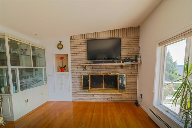 unfurnished living room with baseboard heating, plenty of natural light, a fireplace, and wood-type flooring