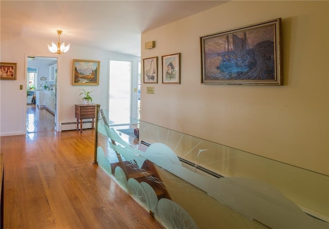 corridor featuring a baseboard heating unit, vaulted ceiling, an inviting chandelier, and light hardwood / wood-style floors