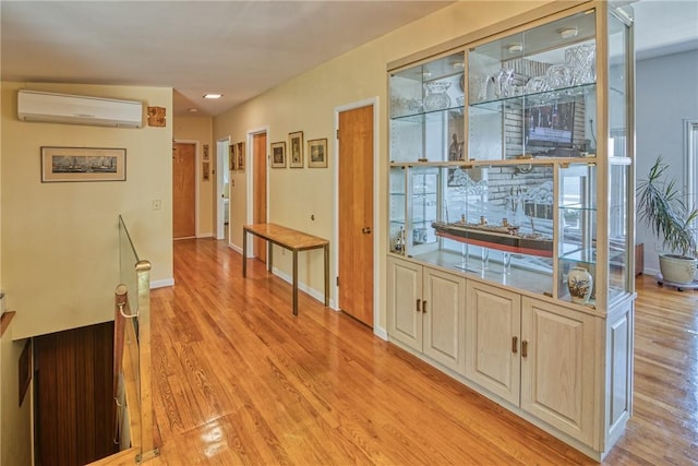 bar with light brown cabinetry, light hardwood / wood-style floors, and a wall mounted air conditioner