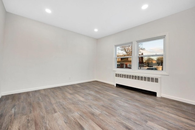 unfurnished room featuring hardwood / wood-style flooring and radiator heating unit