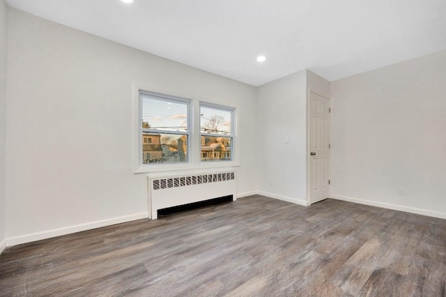 empty room featuring wood-type flooring and radiator heating unit