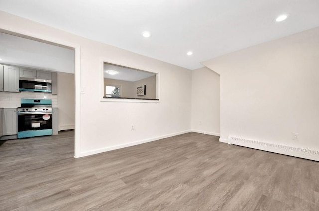 unfurnished living room with baseboard heating and light hardwood / wood-style flooring