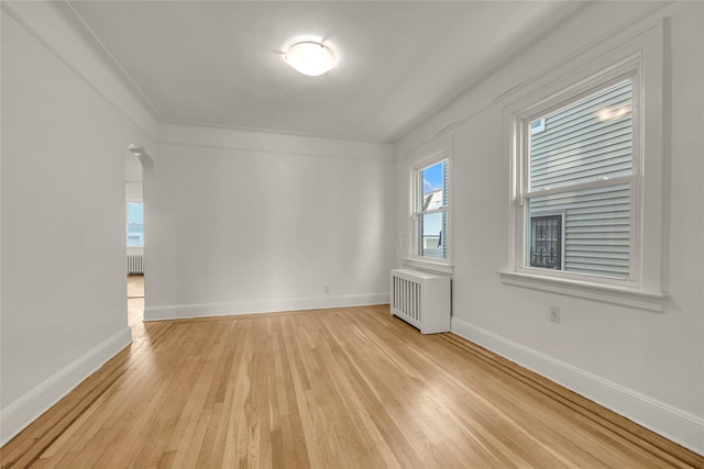 unfurnished room featuring crown molding, radiator, and light hardwood / wood-style floors