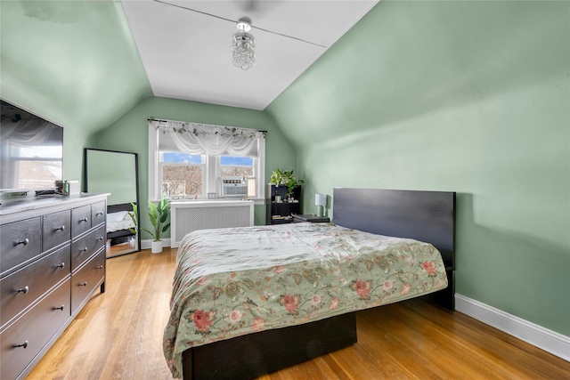 bedroom with cooling unit, vaulted ceiling, and light hardwood / wood-style flooring