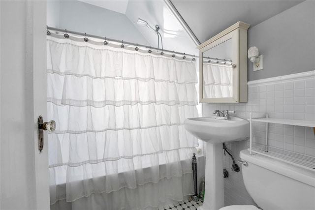 bathroom featuring lofted ceiling, toilet, curtained shower, and tile walls