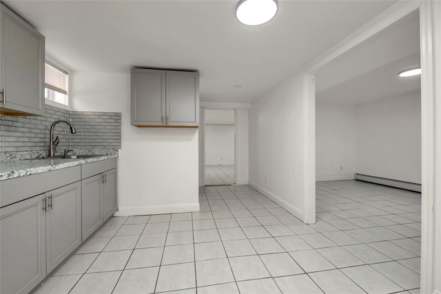 kitchen with sink, gray cabinets, light stone countertops, decorative backsplash, and a baseboard radiator