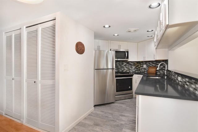 kitchen with sink, tasteful backsplash, stainless steel appliances, light hardwood / wood-style floors, and white cabinets