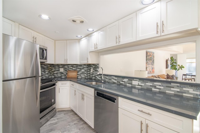 kitchen featuring tasteful backsplash, appliances with stainless steel finishes, sink, and white cabinets