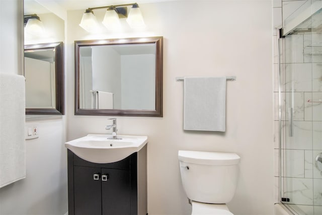 bathroom featuring a shower with door, vanity, and toilet