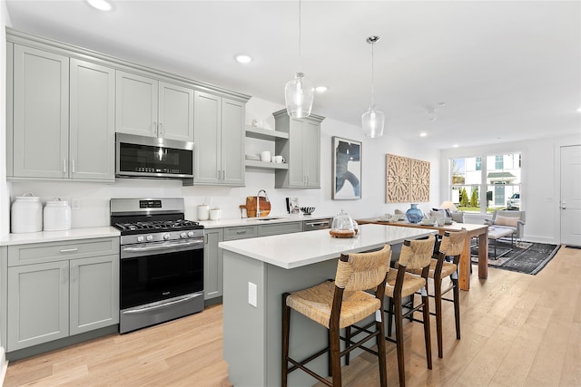 kitchen featuring a kitchen island, gray cabinets, pendant lighting, and stainless steel appliances