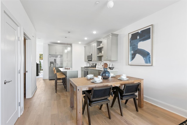 kitchen with appliances with stainless steel finishes, a center island, hanging light fixtures, gray cabinets, and light wood-type flooring