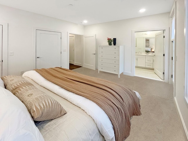 bedroom with light colored carpet and ensuite bath