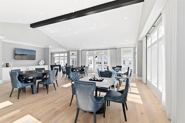 dining room with light wood-type flooring, vaulted ceiling with beams, and ornamental molding