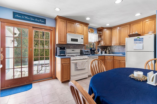 kitchen featuring tasteful backsplash, sink, light tile patterned floors, and white appliances