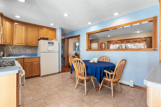 kitchen with sink, white appliances, backsplash, and baseboard heating