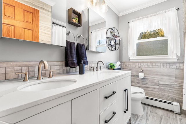 bathroom with crown molding, baseboard heating, tile walls, vanity, and toilet