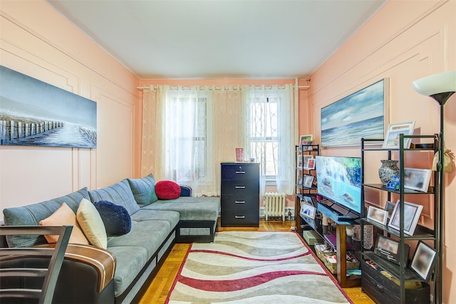 living room with radiator heating unit, light wood-type flooring, and wood walls