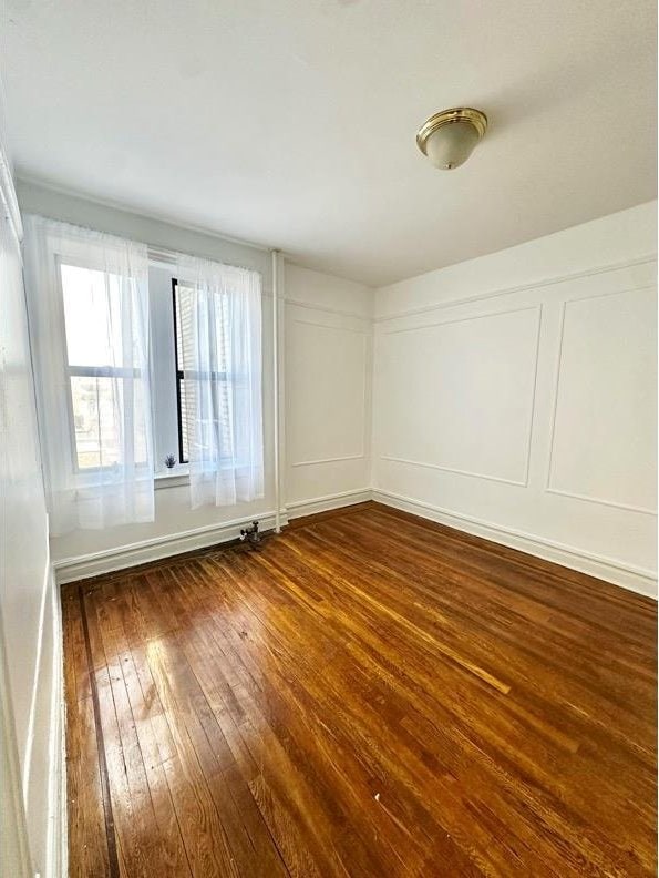 empty room with dark wood finished floors and a decorative wall