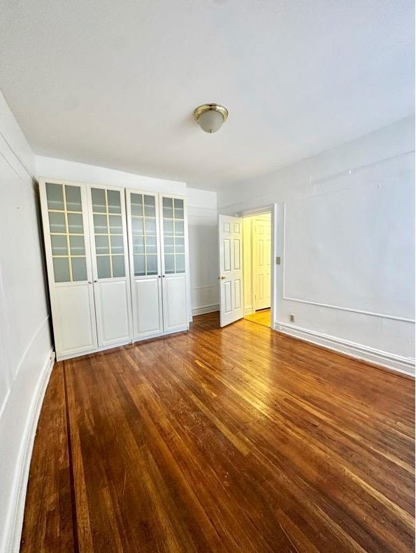 unfurnished bedroom featuring wood finished floors and baseboards