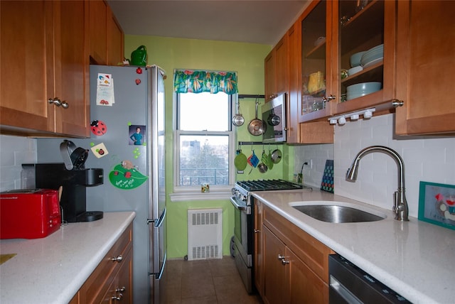 kitchen with a sink, stainless steel appliances, light countertops, dark tile patterned floors, and brown cabinets