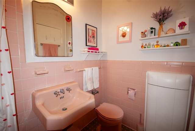 bathroom with a wainscoted wall, toilet, tile walls, and a sink