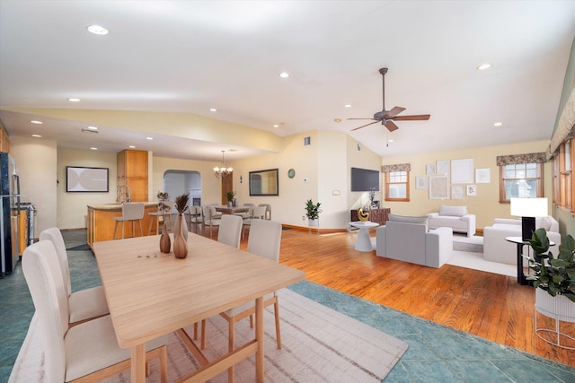 dining area featuring sink, hardwood / wood-style flooring, ceiling fan with notable chandelier, and lofted ceiling