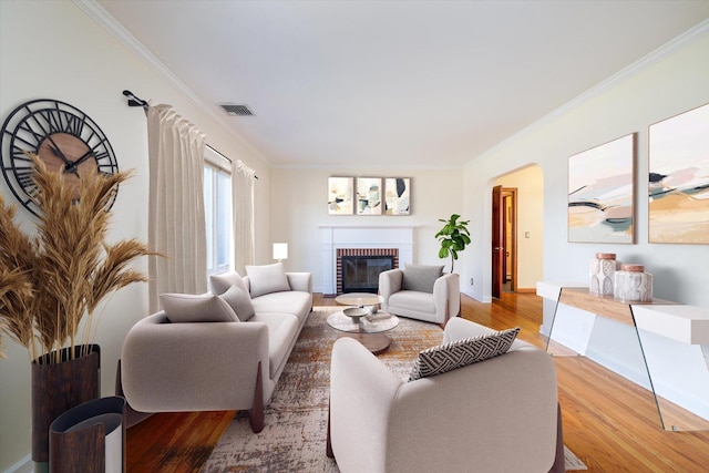 living room with hardwood / wood-style floors, crown molding, and a fireplace