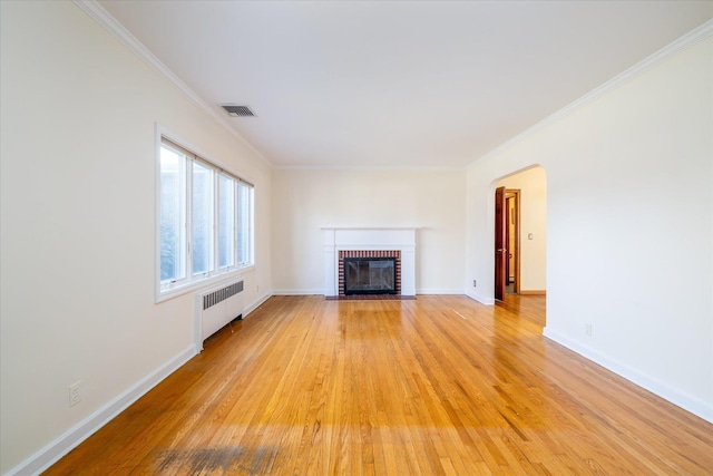 unfurnished living room featuring radiator heating unit, a brick fireplace, crown molding, and light hardwood / wood-style floors