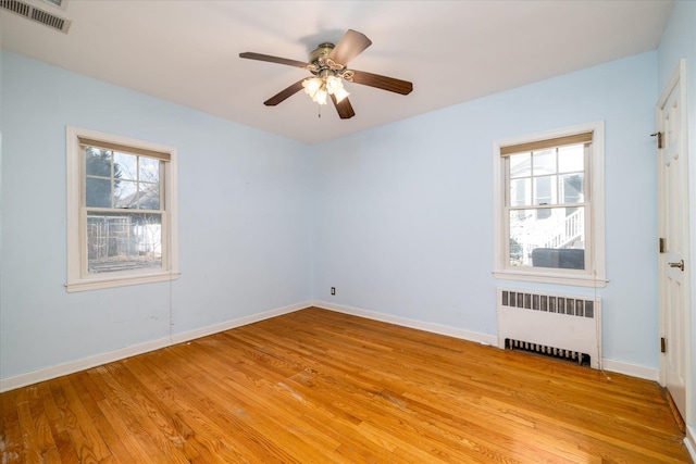 unfurnished room with light wood-type flooring, ceiling fan, and radiator