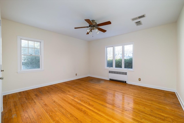 spare room with ceiling fan, radiator heating unit, and light hardwood / wood-style floors