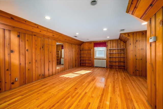 unfurnished living room featuring wooden walls, radiator, and light hardwood / wood-style flooring