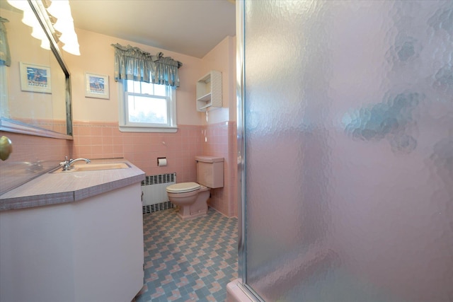 bathroom featuring radiator heating unit, a shower with door, vanity, tile walls, and toilet